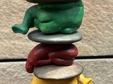 a sculpture of a man sitting on top of a stack of rocks