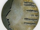 une médaille d'argent sur laquelle est représenté le visage d'un homme