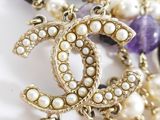 chanel necklace with pearls and amethorate beads on a white surface