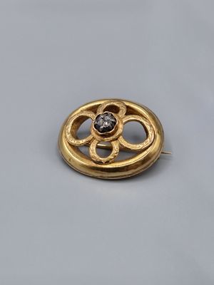 un gros plan sur une broche en or ornée d'un diamant au centre