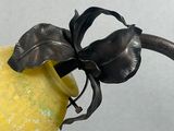 a yellow vase with a leaf on it sitting on a table