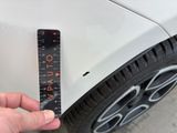someone is measuring the width of a car ' s tire with a ruler