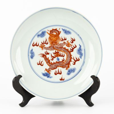 une assiette ornée d'un dragon, posée sur un socle