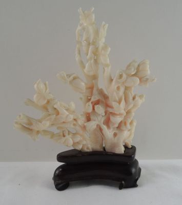 un corail blanc posé sur un socle noir, lui-même posé sur une surface blanche