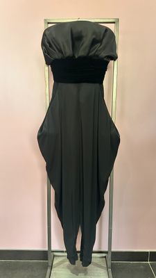 the back of a black dress hanging on a rack in front of a pink wall