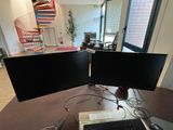 two computer monitors sitting on a desk with a keyboard and mouse