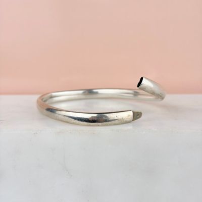 a close up of a silver bang bracelet on a marble surface