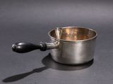 a small silver cup with a wooden handle on a table