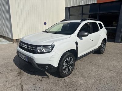 une Dacia blanche garée devant un immeuble