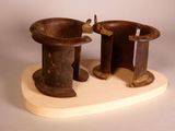 two wooden vases sitting on a stand on a white surface