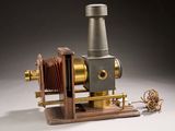 a small antique camera on a wooden stand with a rope