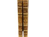 two old books sitting on top of each other on a white surface