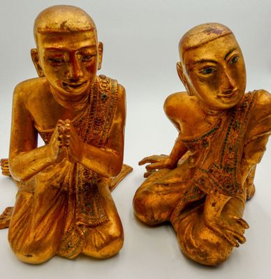 pair of gold statues of a man and a woman sitting on the ground