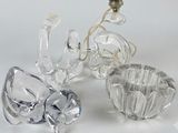 trois figurines en cristal posées sur une table à côté d'une ampoule