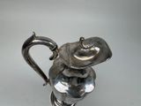 a silver tea pot with a handle on a table