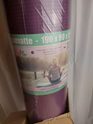 un rouleau de tapis de yoga violet dans une boîte en carton