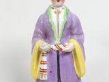 une figurine représentant une femme coiffée d'un chapeau et tenant un panier