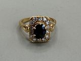a close up of a gold ring with a black stone surrounded by white diamonds