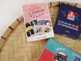three books sitting on top of a basket on a table