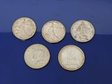 six pièces de monnaie britanniques différentes posées sur une surface bleue