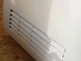 a white air conditioner sitting on the floor next to a wall