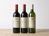 trois bouteilles de vin sont alignées sur une table en bois