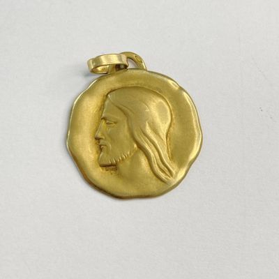 un gros plan d'une pièce d'or sur laquelle est représenté le visage de Jésus