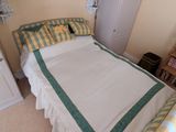 un lit recouvert d'une couette blanche et verte dans une chambre