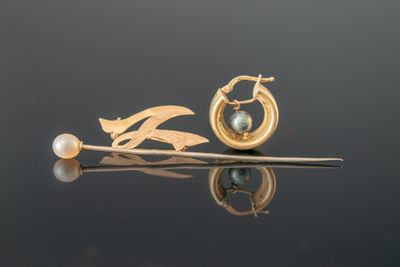 une boucle d'oreille en or ornée d'une perle et d'une feuille