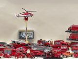 many toy fire trucks and a helicopter on a table