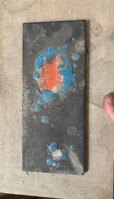 une petite œuvre d'art posée sur une table, avec la main d'une personne