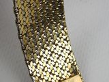 a close up of a gold bracelet on a white surface
