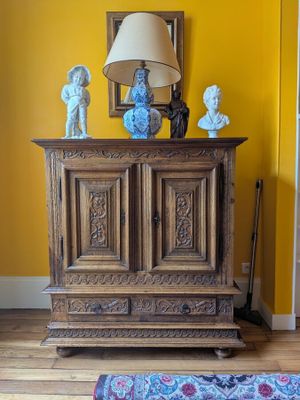 a wooden cabinet in a room with a lamp on top of it