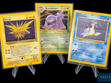 Trois cartes Pokémon différentes sont représentées sur un fond noir