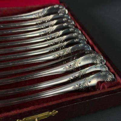 six cuillères en argent dans une boîte rouge posée sur une table