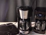 deux cafetières posées sur une table, à côté d'un ordinateur portable