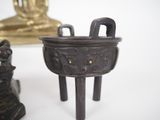 a small bronze pot sitting on a table next to a statue