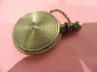 une montre de poche en or avec une chaîne, posée sur un fond rose