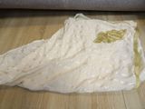 a white dress with gold sequins on it sitting on a wooden floor