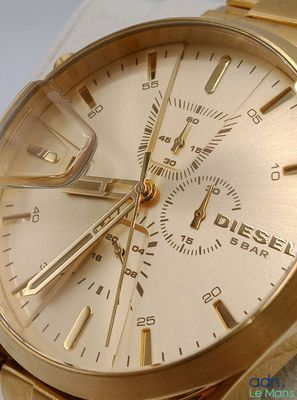 gros plan d'une montre en or sur une surface blanche