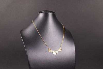 un collier en or présenté sur un mannequin, sur fond noir