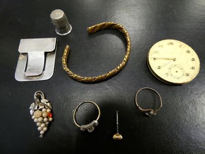 de nombreux bijoux posés sur une table, avec une horloge en arrière-plan