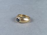 a close up of a gold ring with a black stone