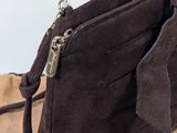 someone is holding a brown purse with a zipper on it