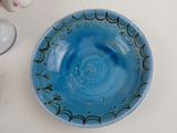 a blue bowl sitting on a table next to a glass of wine