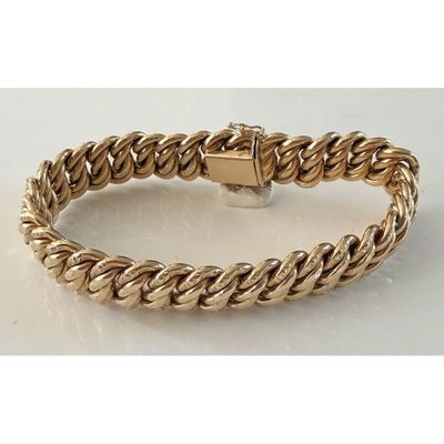 gros plan d'un bracelet en or sur une surface blanche