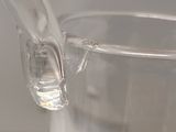 a clear glass pitcher with a handle on a table