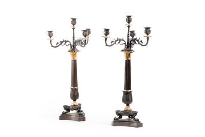 une paire de chandeliers noirs et dorés avec des bougies sur leurs socles