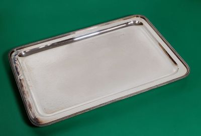 un plateau en argent posé sur une table verte, sur fond vert