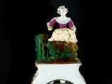 figurine of a woman sitting on a chair with a basket in her hand